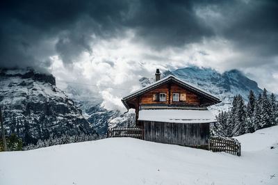 House on snow covered mountain against sky