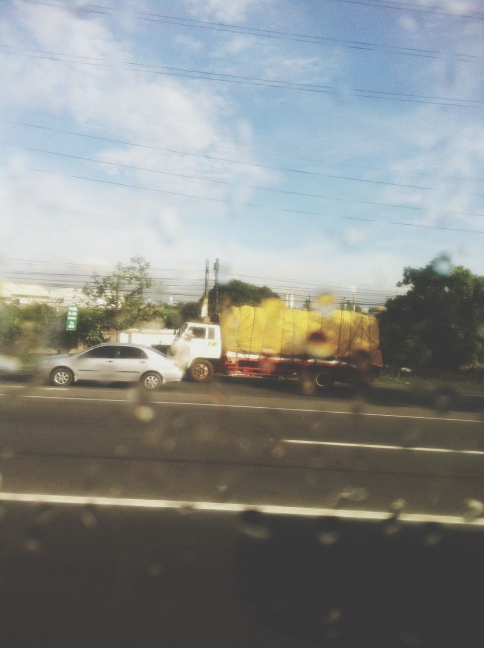 transportation, land vehicle, car, mode of transport, road, street, sky, road marking, tree, cloud - sky, on the move, windshield, travel, glass - material, the way forward, transparent, building exterior, cloud, day, vehicle interior