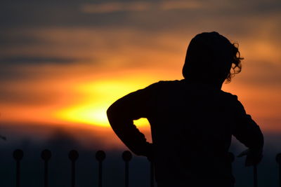 Silhouette man standing against orange sky during sunset
