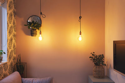 Illuminated lamp hanging on ceiling at home