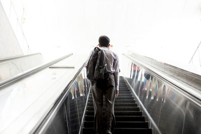 Rear view of man standing on escalator