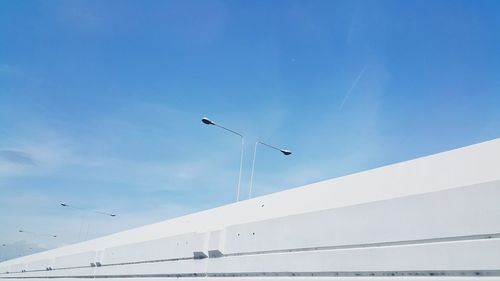 Low angle view of lamp posts against blue sky