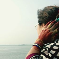 Side view of woman with henna tattoo against sea