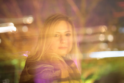 Portrait of young woman holding illuminated string lights