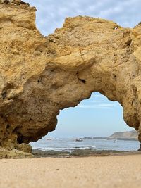 Rock formation on beach against sky