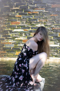 Young woman sitting against wall