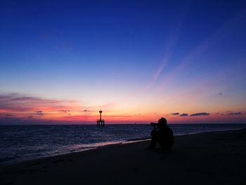Silhouette man on beach against sky during sunset