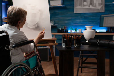 Rear view of man sitting on table