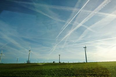 Wind turbines on field against sky