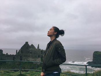 Young woman standing against old ruins by sea