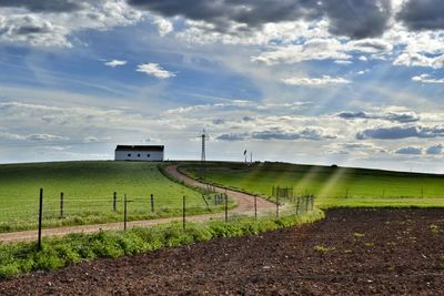 Scenic view of grassy field against cloudy sky