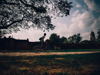 Man riding bicycle on field against sky