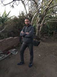 Portrait of young man standing against trees