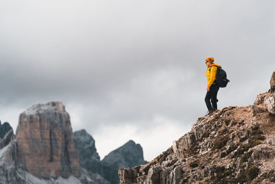 Low angle view of man walking on rock against sky