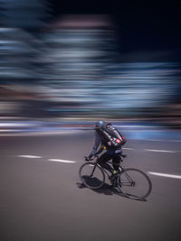 Blurred motion of person riding bicycle on road