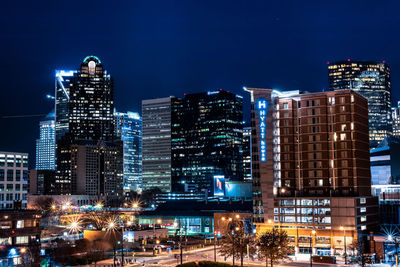 Illuminated buildings in city against sky at night