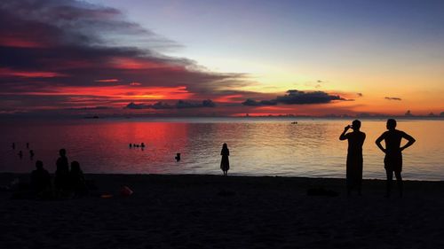 Silhouette people at beach during sunset