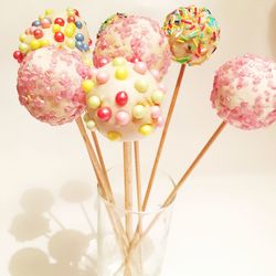 Close-up of sprinkles on cake pops in container against wall