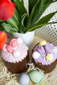 Colorful easter eggs lie along with easter baked goods decorated with colored chocolate.