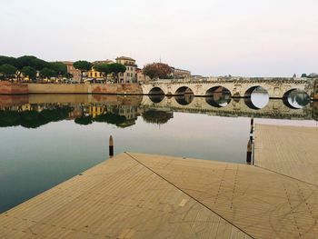 Arch bridge over river by building against sky