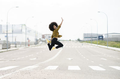 Young woman jumping on road in city