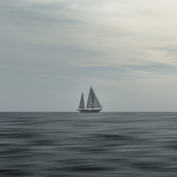 Scenic view of boat on calm sea against cloudy sky