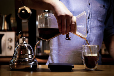 Man pouring coffee in cup on table