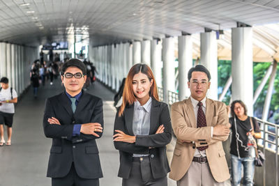 Portrait of colleagues with arms crossed standing on bridge in city