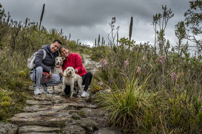 Young couple smiling with dogs on high mountain stone path front view