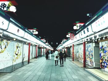 Rear view of people walking on footpath at night