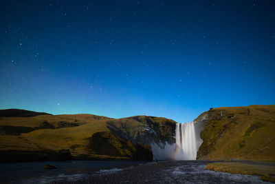 Scenic view of waterfall against clear blue sky