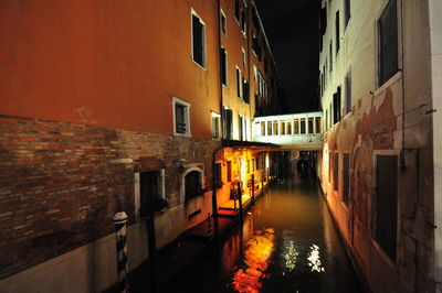 Canal amidst buildings in city at night