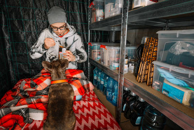 Man eating canned food by french bulldog dog in emergency underground shelter