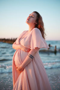 Young pregnant woman with a beautiful sea view on the background. happy and calm pregnant woman