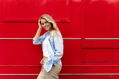Young woman standing against yellow wall