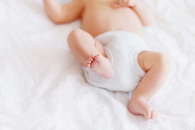Baby's feet. little child wearing white bodysuit and diaper. cozy morning at home.