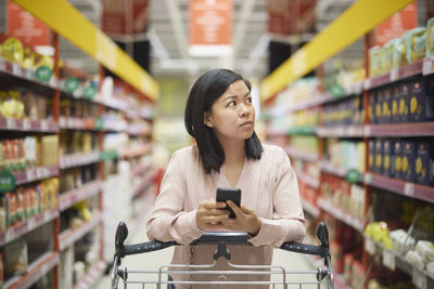 Woman looking at prices during inflation while doing shopping in supermarket