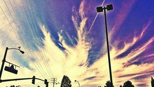 Low angle view of power lines against cloudy sky