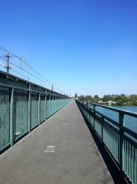 Footbridge over road against clear blue sky