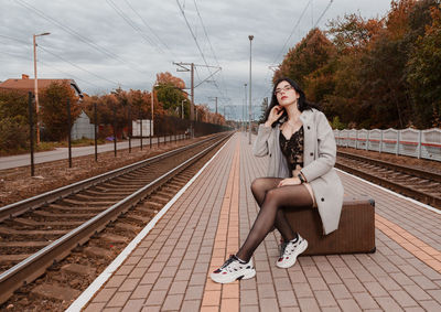 Woman sitting on railroad station platform