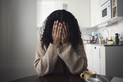 Young woman covering face with hands