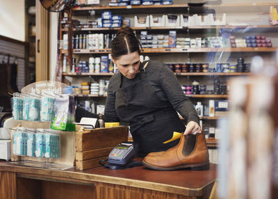 Female shoemaker reading name tag at shoe store