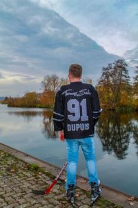 Rear view of man standing by lake against sky