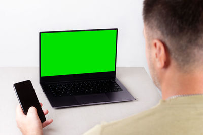 Rear view of man using laptop on table