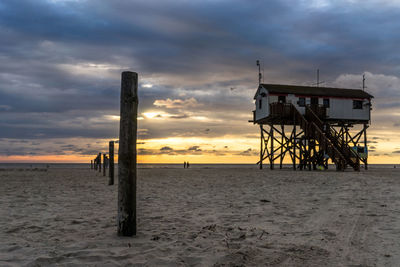 Lifeguard hut on beach against sky during sunset