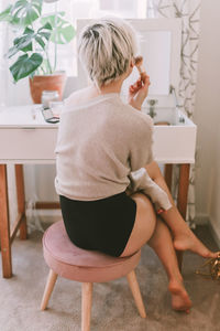 Rear view of woman sitting on chair at home