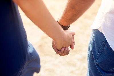 Midsection of couple holding hands