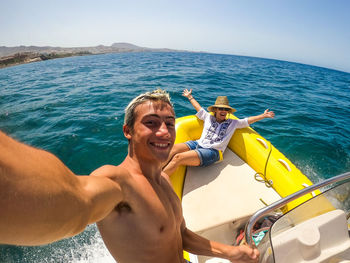 Portrait of smiling teenage boy with mother sitting in boat