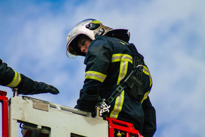 Low angle view of men working against sky