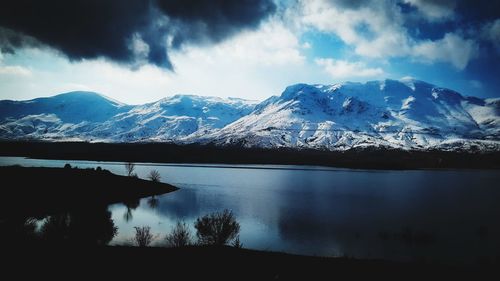 Scenic view of lake and snowcapped mountains against sky